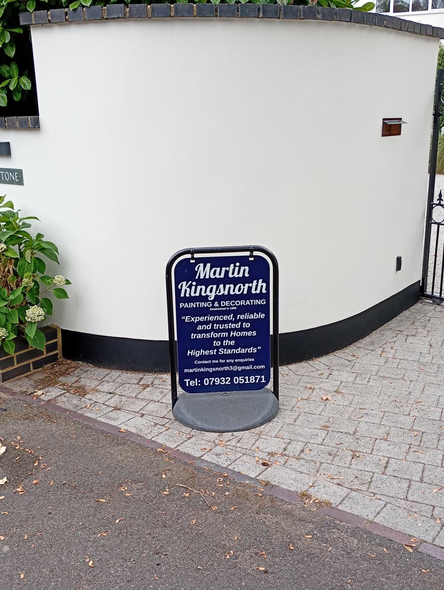 White painted curved garden wall with a black plinth and a Martin Kingsnorth A-board in front