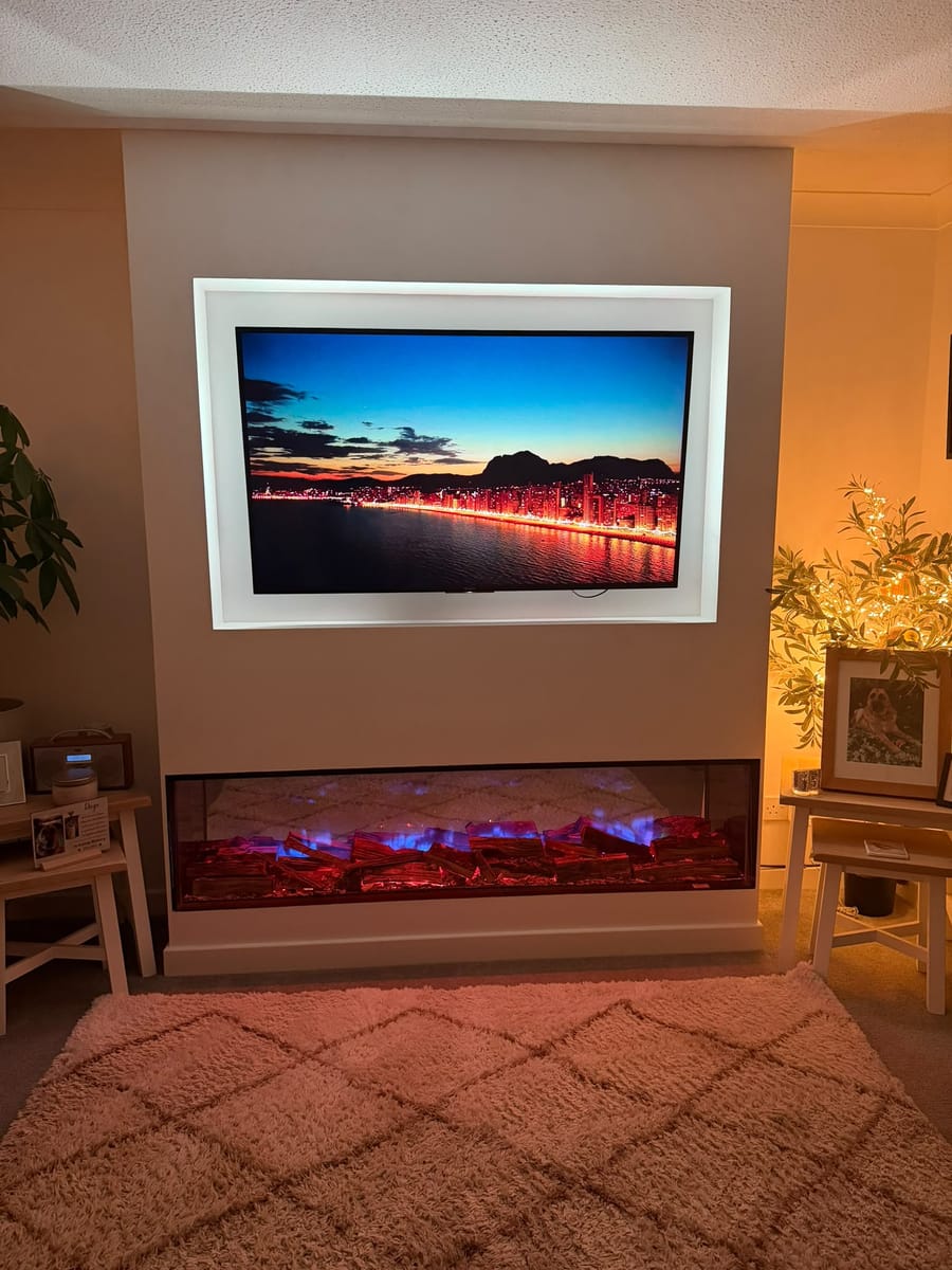 Media wall with warm white lighting around the TV recess and a flame-effect fire below