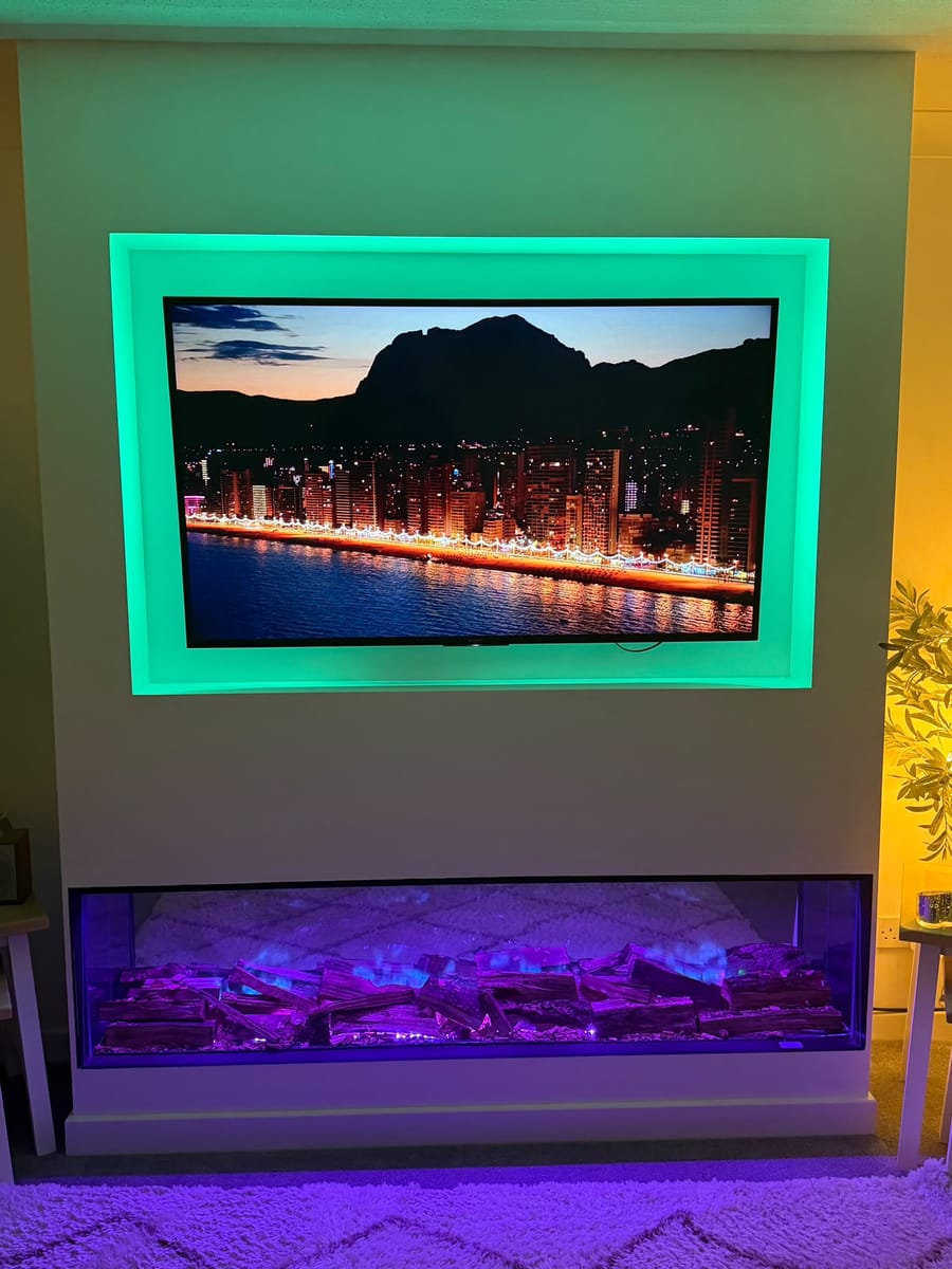 Media wall with green lighting around the TV recess