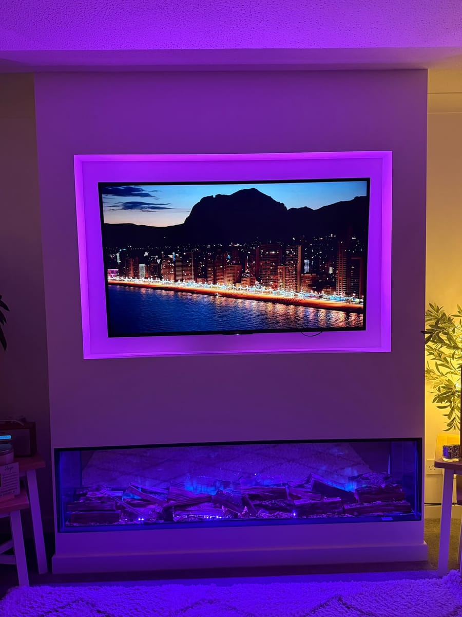 Media wall with pink lighting around the TV recess