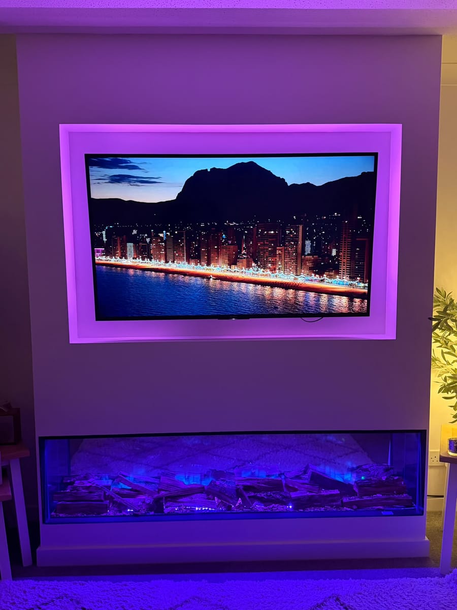Media wall in purple light with pink lighting around the TV recess