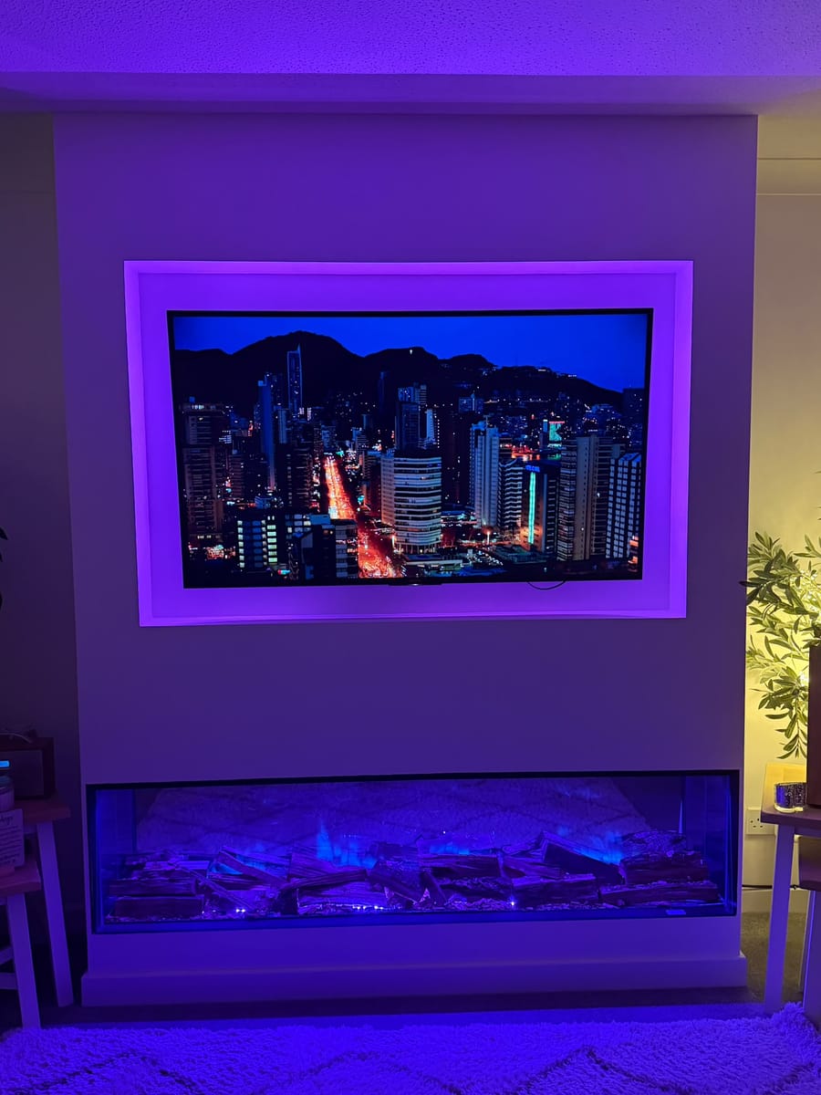 Media wall in purple light with a city skyline on the TV