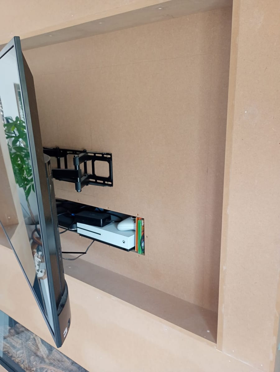 TV swung out on its wall bracket from the bare MDF media wall