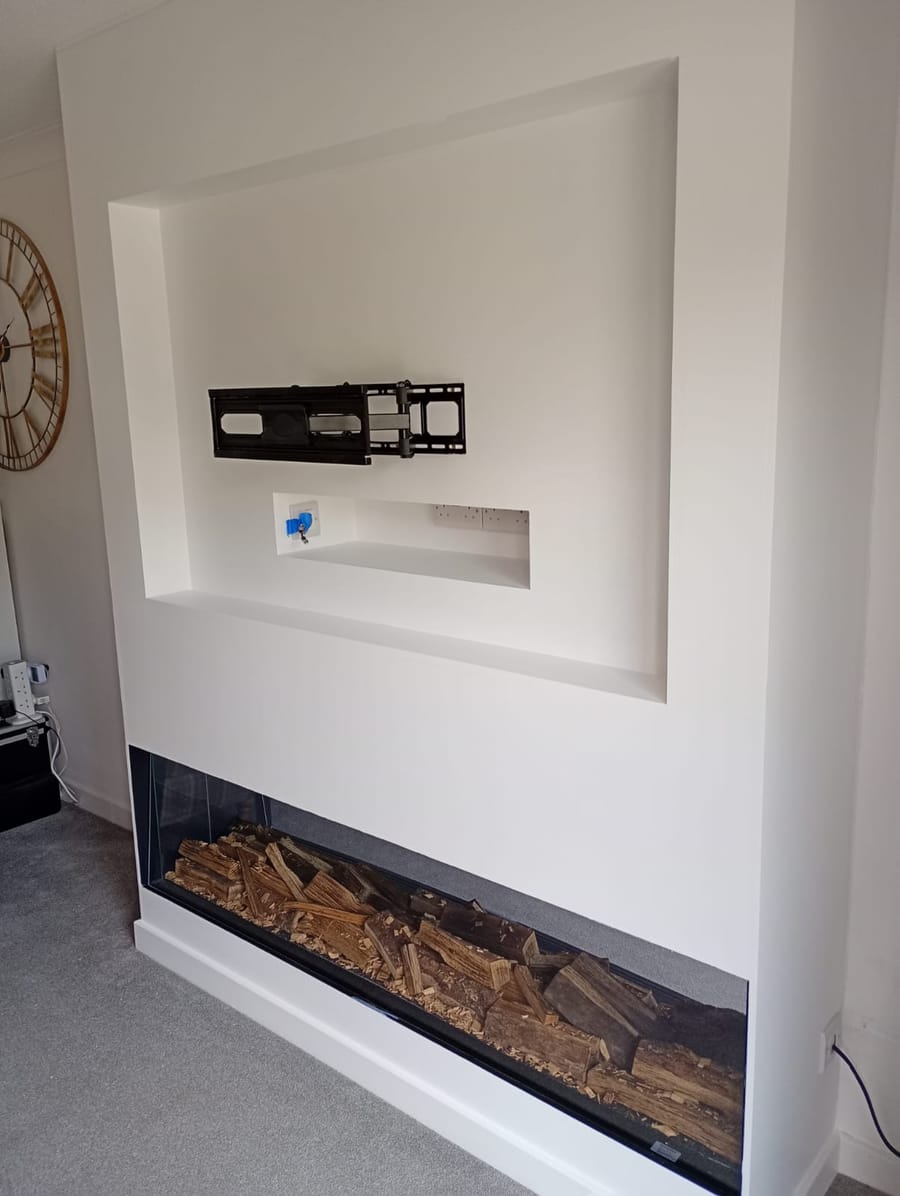 Media wall painted white with the TV bracket fitted above a log-effect fire