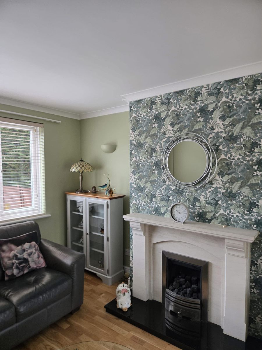 Sage green sitting room with a floral wallpaper chimney breast
