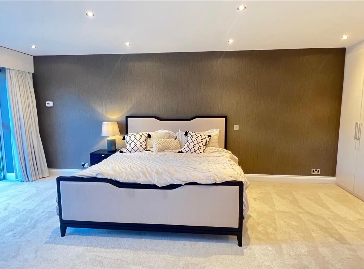 Bedroom with a full-width feature wall in textured brown wallpaper behind the bed