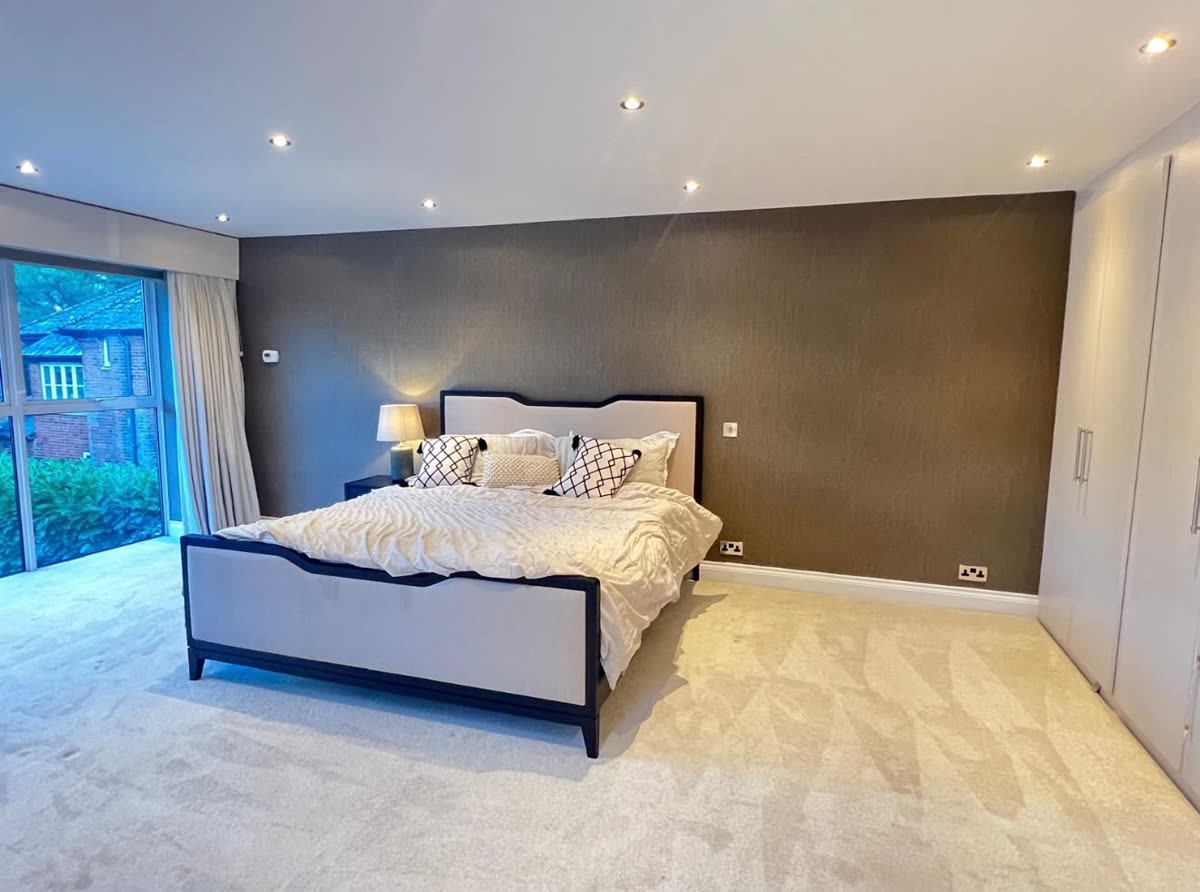 Textured brown wallpaper on a bedroom wall, seen from the side with the window on the left