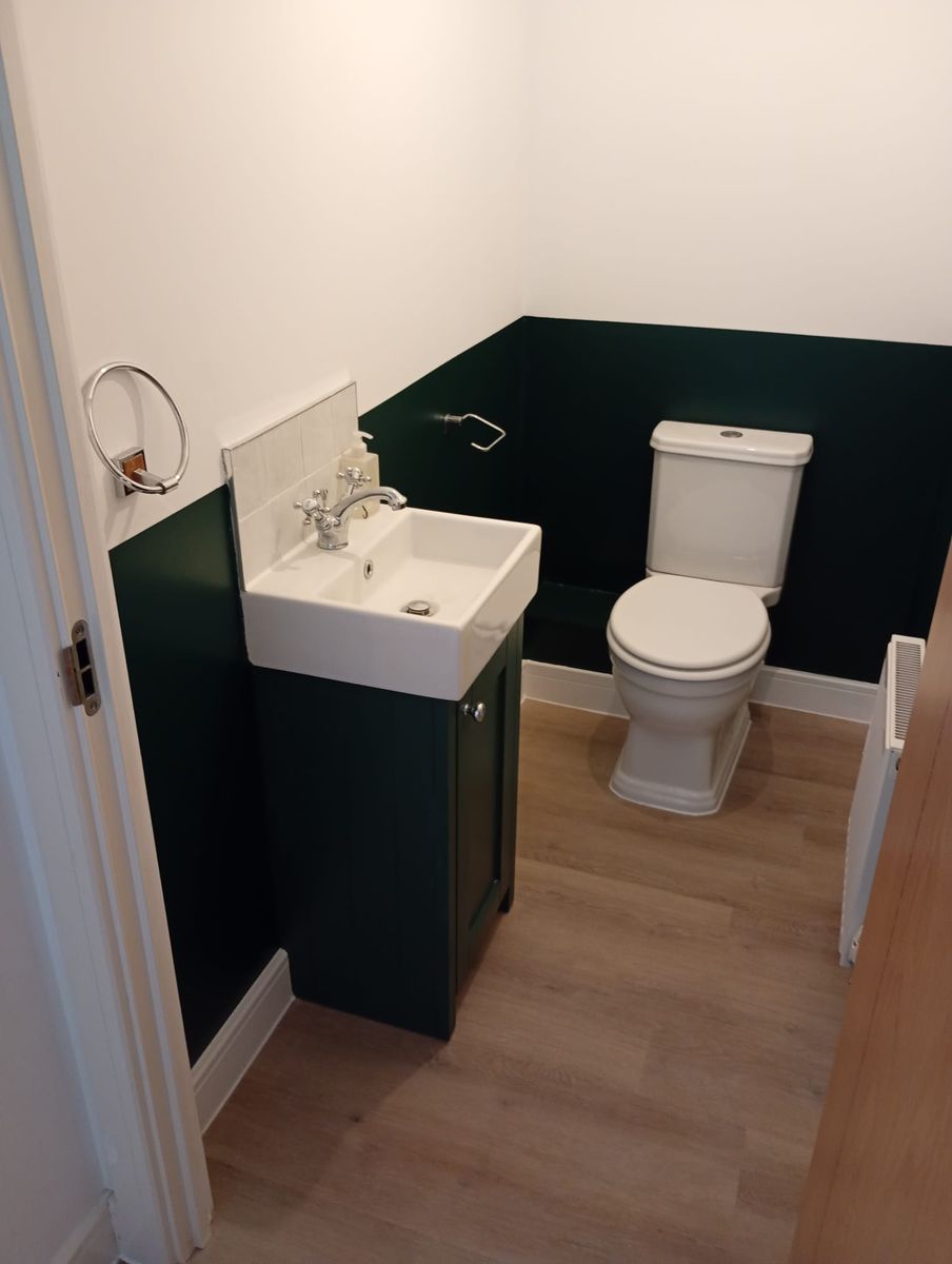 Cloakroom painted dark green below a white upper wall