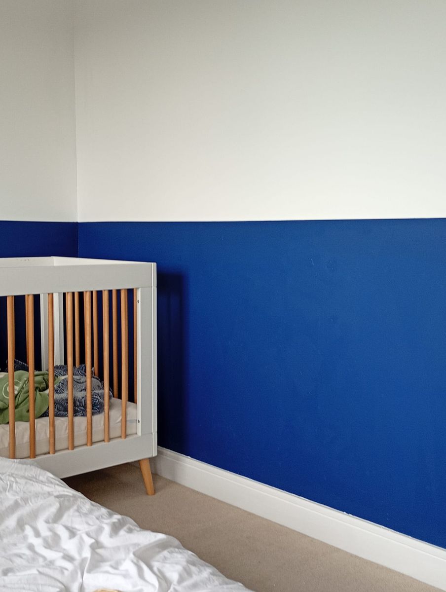 Bedroom with a navy lower wall beside a cot